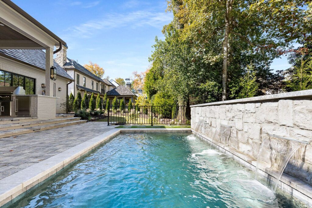 Swimming pool, stone retaining wall and rear elevation of a custom home built by VIBE Luxury Homes in Brookhaven, Atlanta