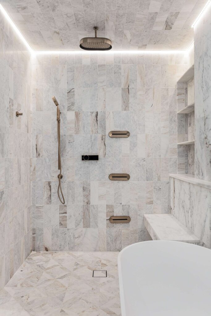 Marble shower with brass fixtures in a custom home built by VIBE Luxury Homes in Brookhaven, Atlanta